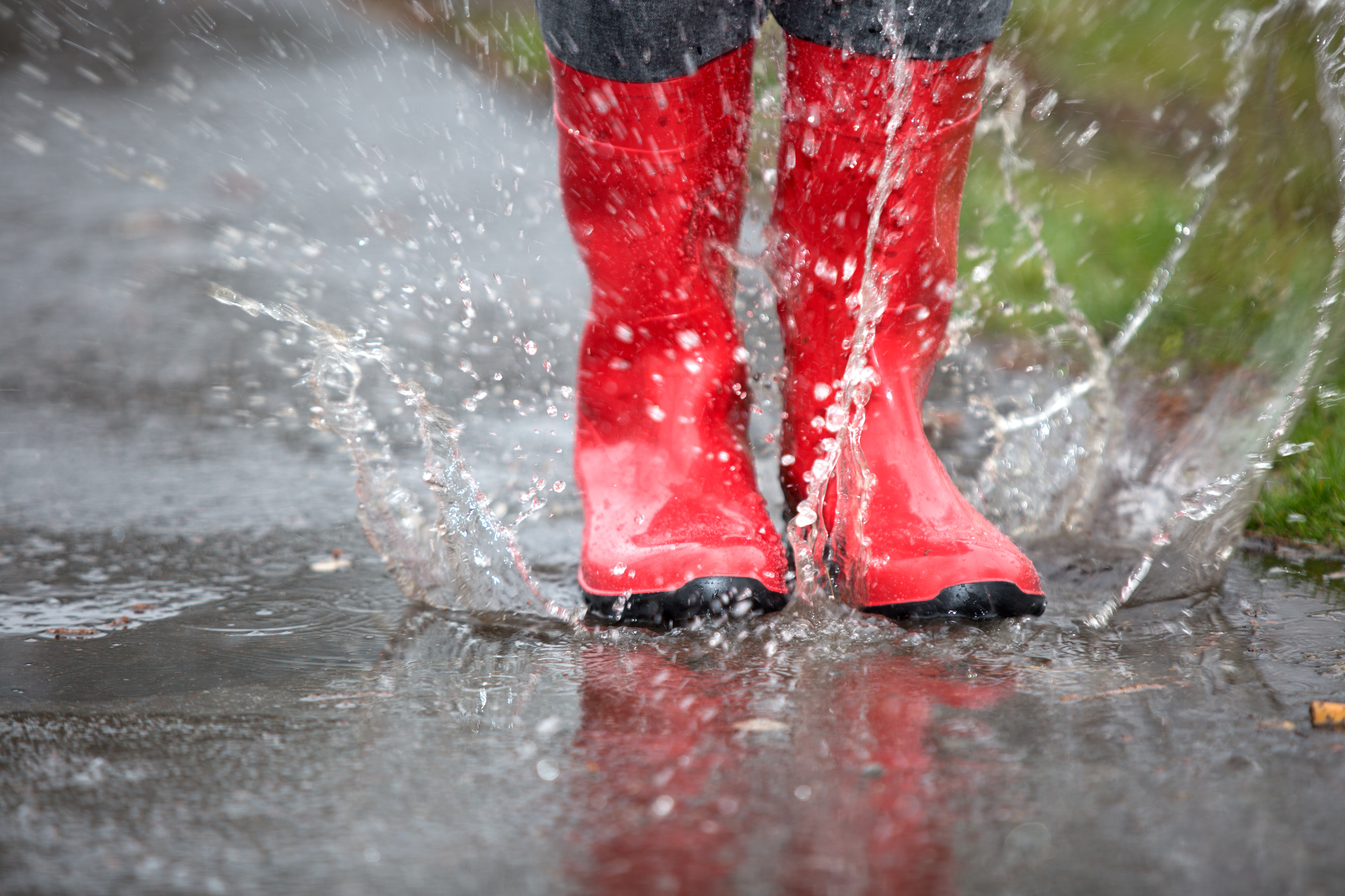 Regenwetter, Rote Gummistiefel in Pfütze